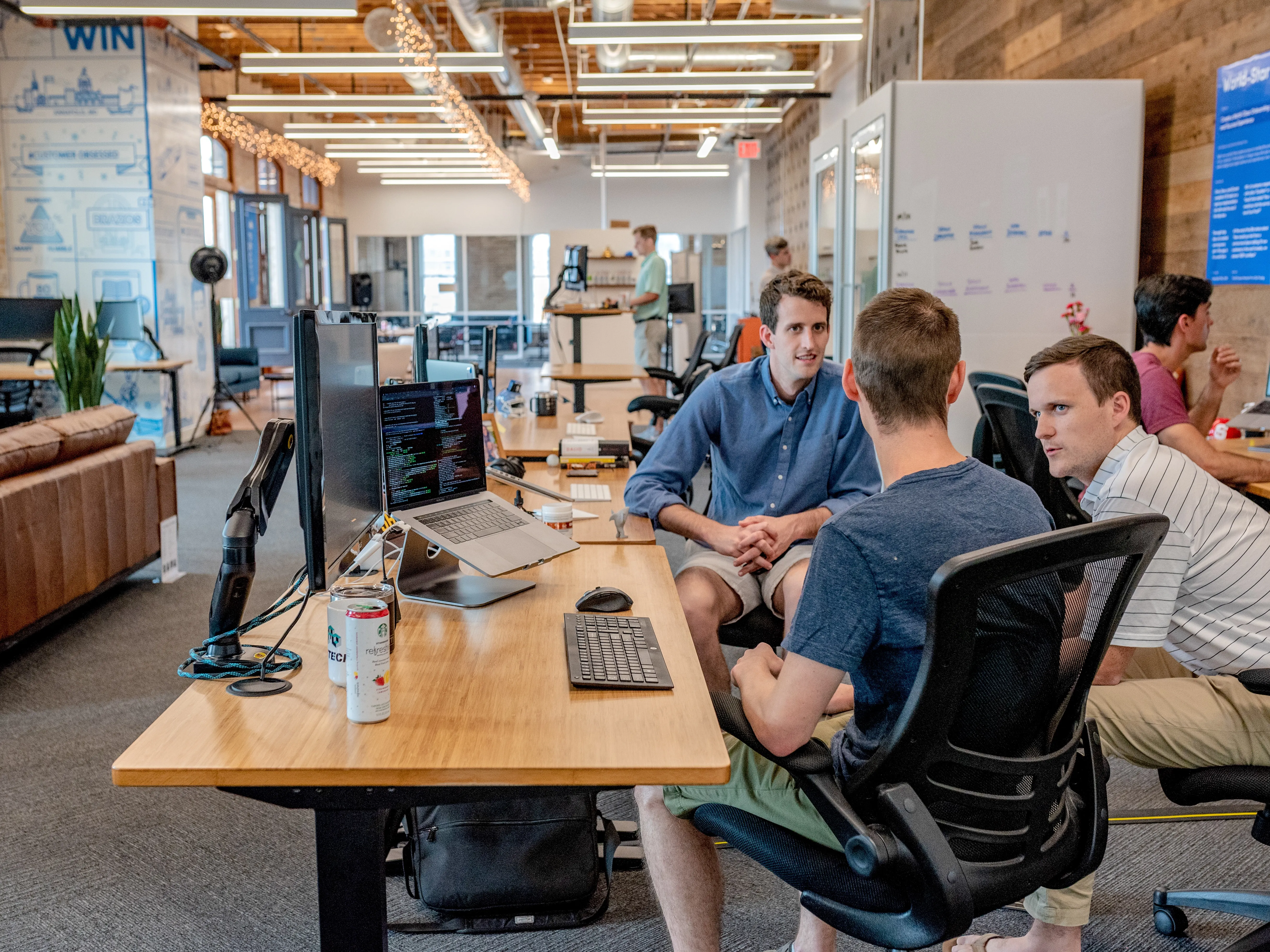 Three men sitting around a computer desk