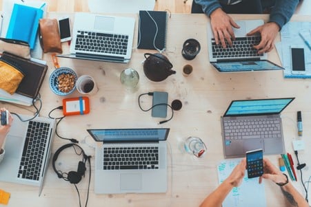 people sitting down at table with assorted laptops